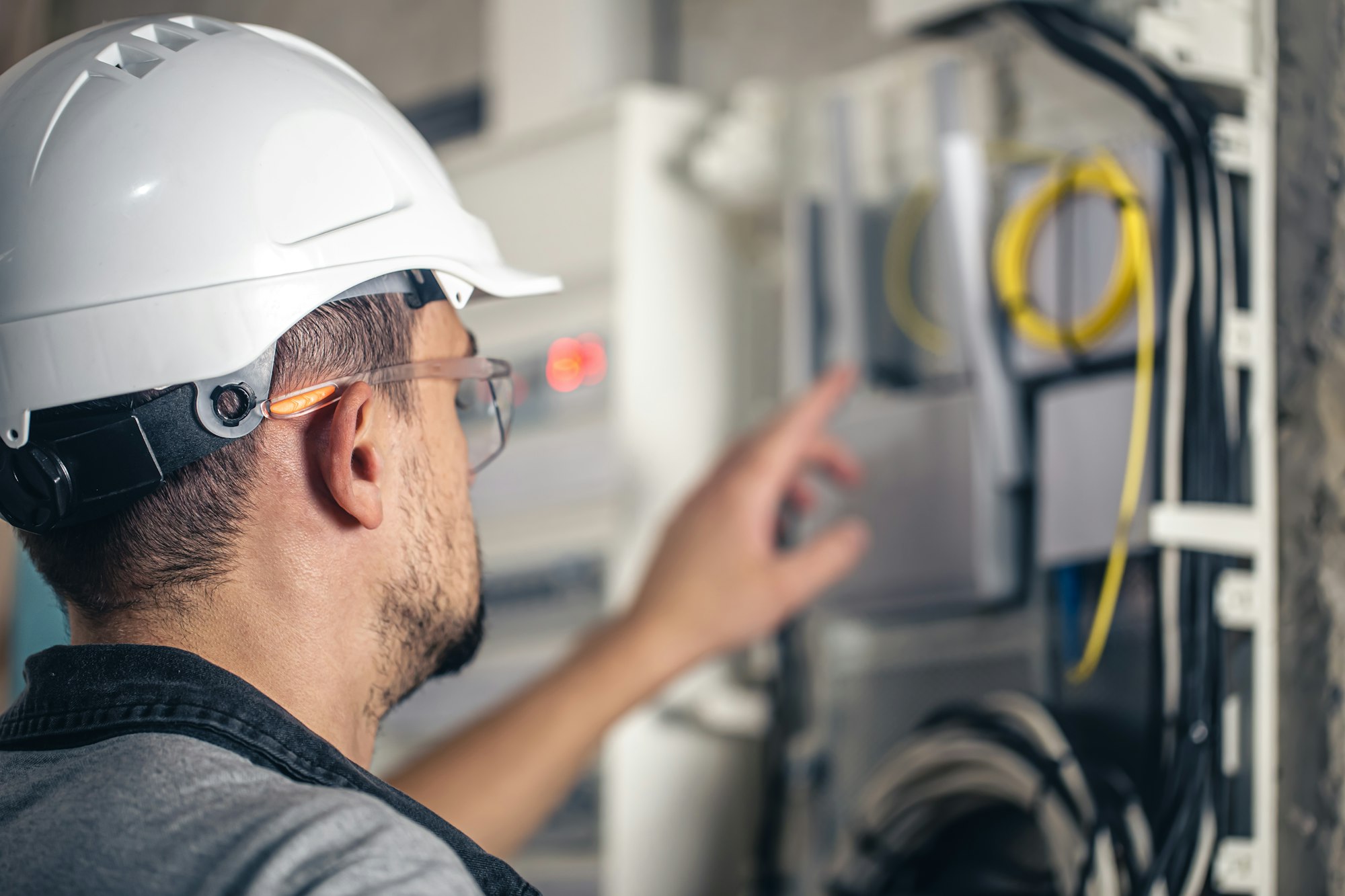 Man, an electrical technician working in a switchboard with fuses.